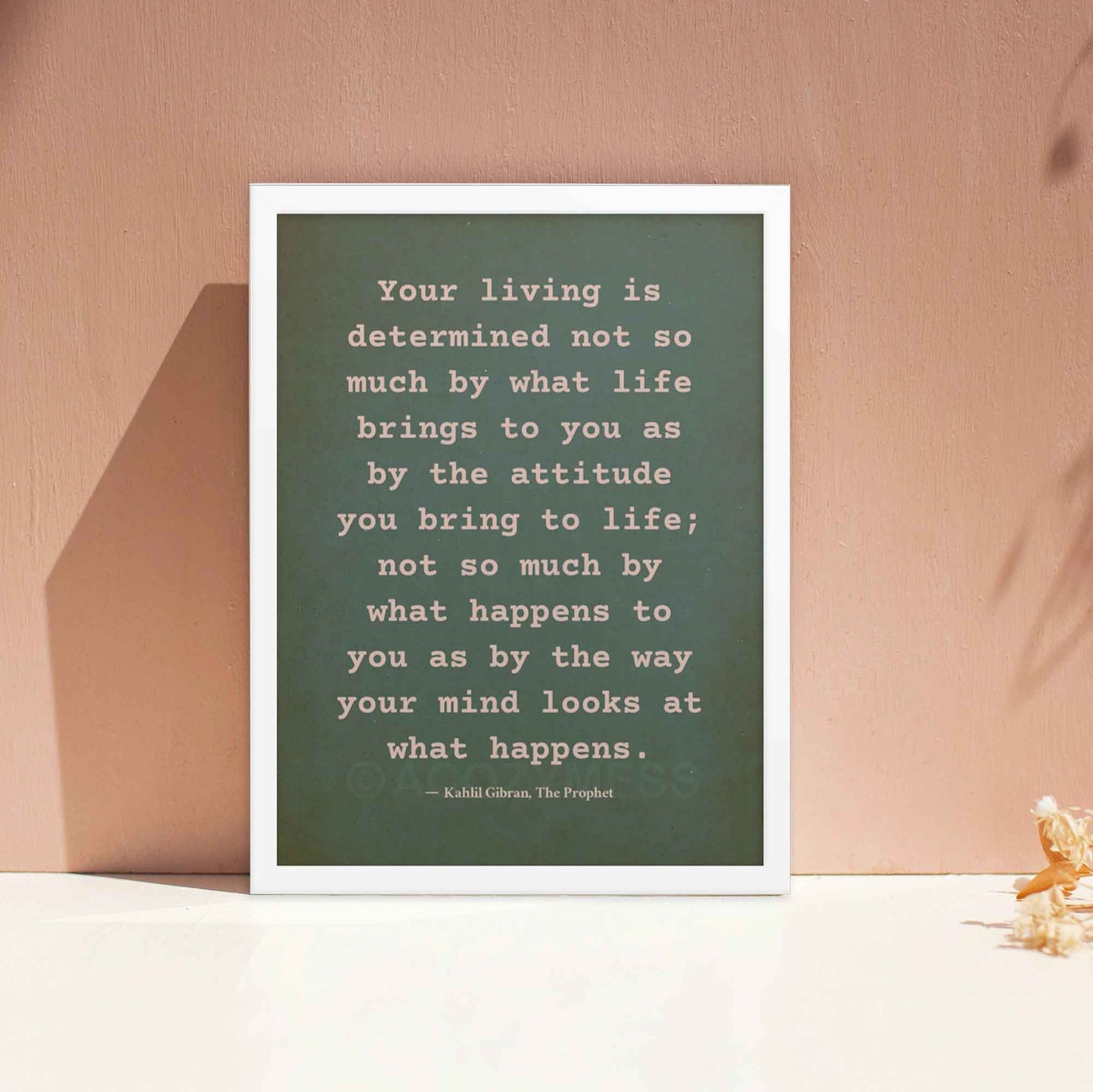 On attitude By kahlil gibran poster beige on textured green, displayed in white frame.