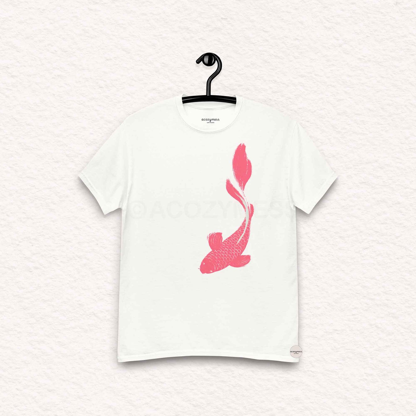 White t-shirt with pink fish design on a hanger against a white background