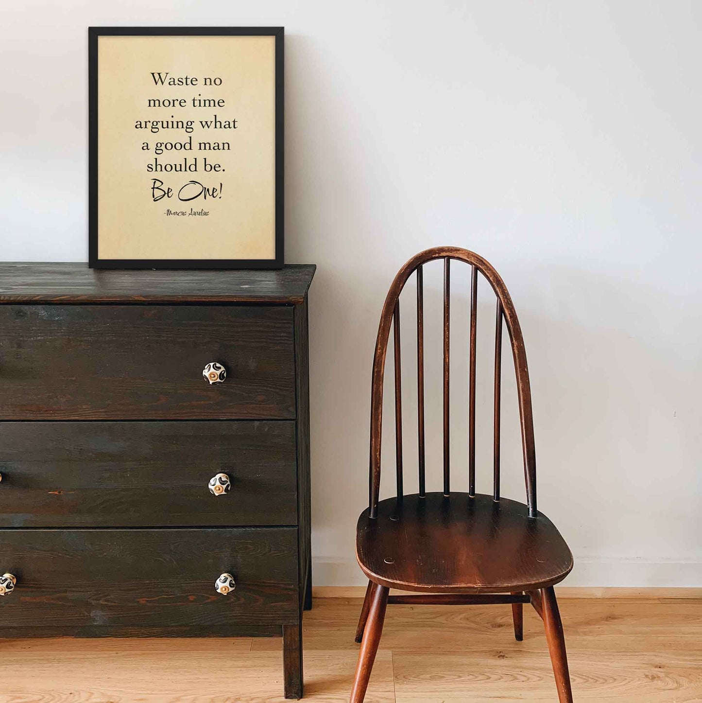 Black-on-beige literary print featuring the quote by Marcus Aurelius, styled with an old paper look and displayed in a black frame on a shelf adding a timeless and motivational touch to any space.