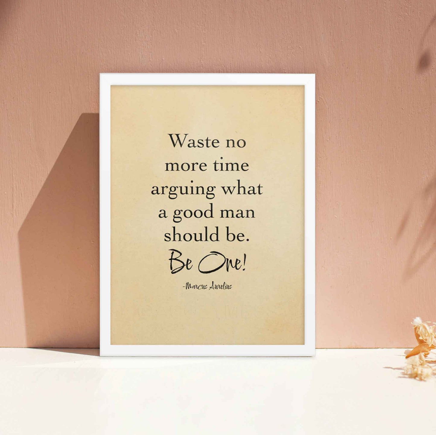 Black-on-beige literary print featuring the quote by Marcus Aurelius, styled with an old paper look and displayed in a white frame.