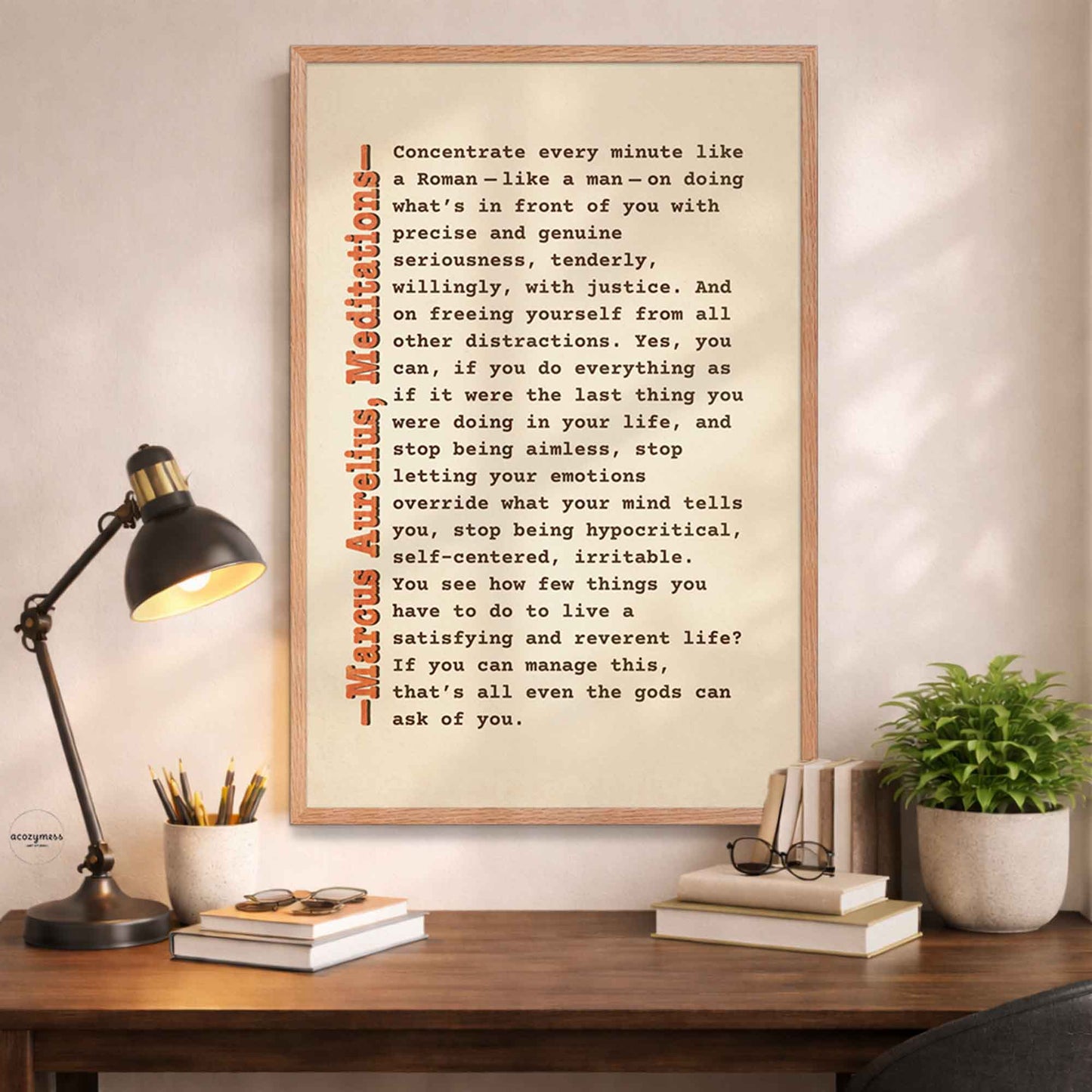 Framed motivational quote on a wall above a desk with a lamp and books.
