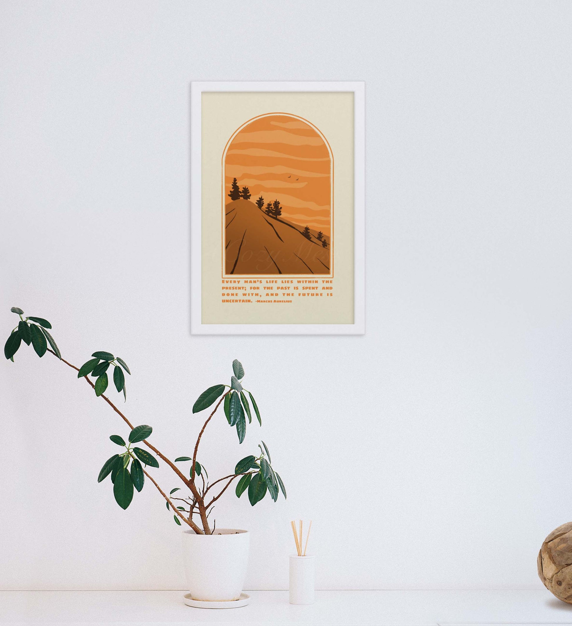 A framed art poster depicting an arch-shaped window view of a stylized landscape with a road leading towards the horizon, flanked by silhouetted pine trees against a backdrop of orange sky with layered clouds. At the bottom is a quote from Marcus Aurelius in a clea