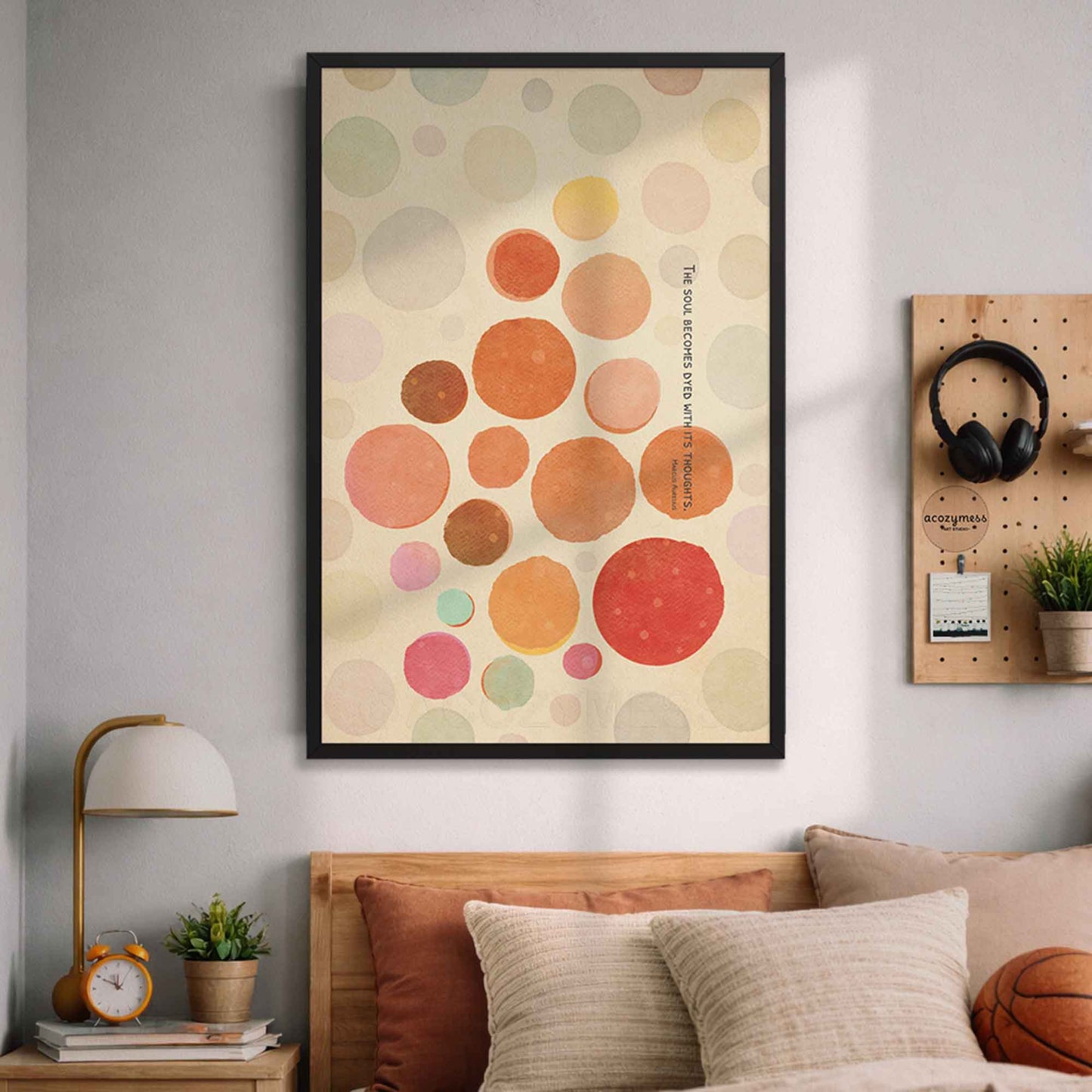 Black Framed abstract art print with colorful circles and Stoic quote on a wall above a bed in a bedroom.