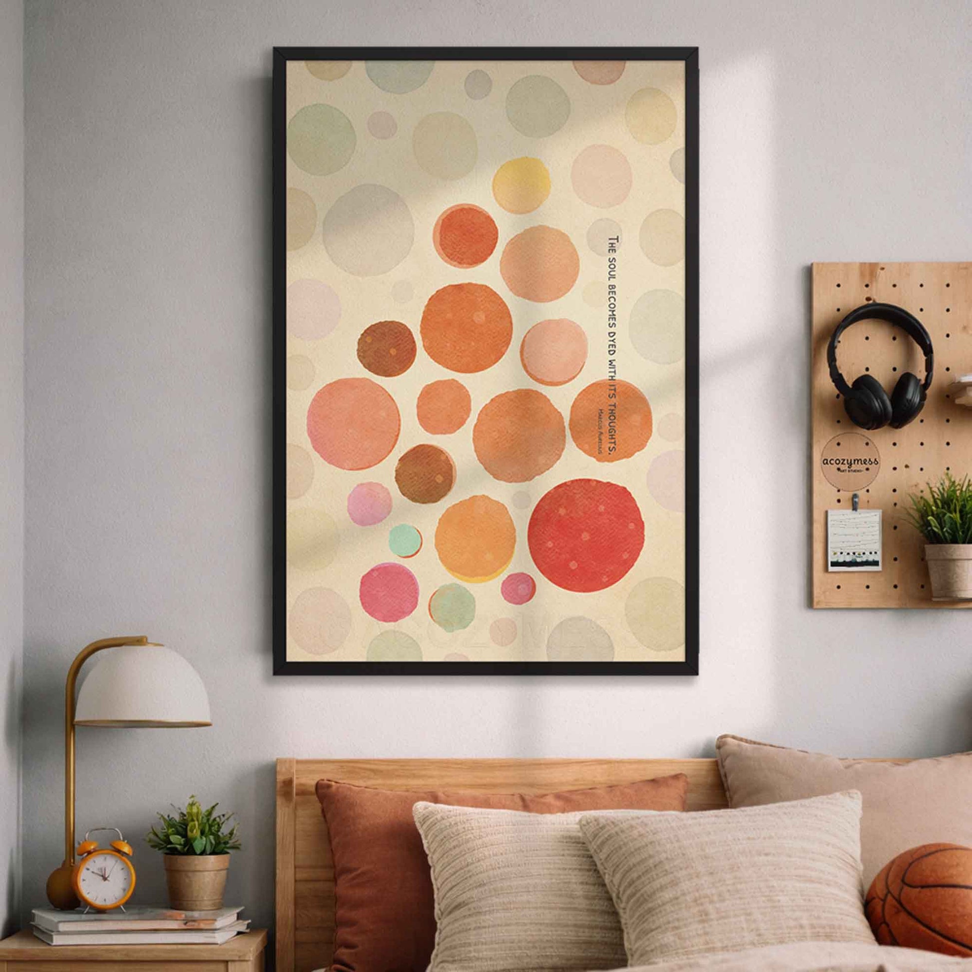 Black Framed abstract art print with colorful circles and Stoic quote on a wall above a bed in a bedroom.