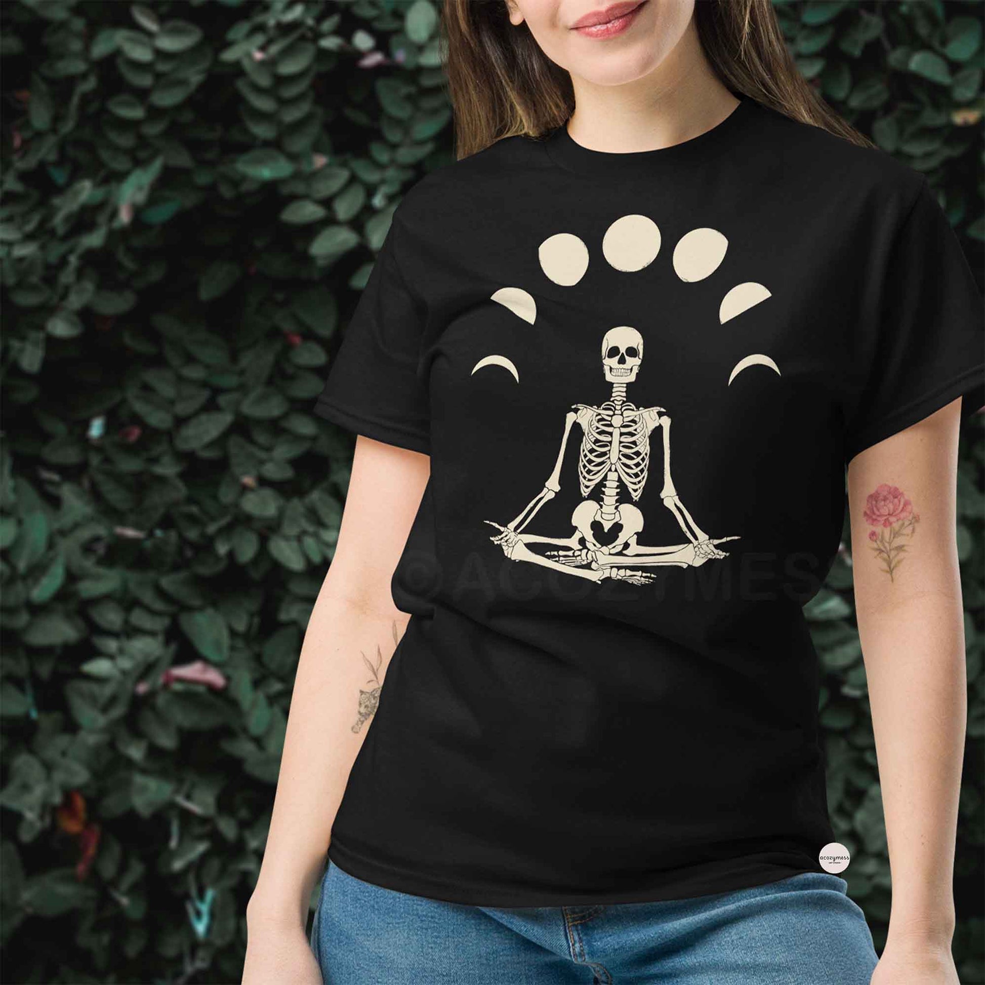 Person wearing a black t-shirt with a skeleton in a meditative pose design and moon phase illustration