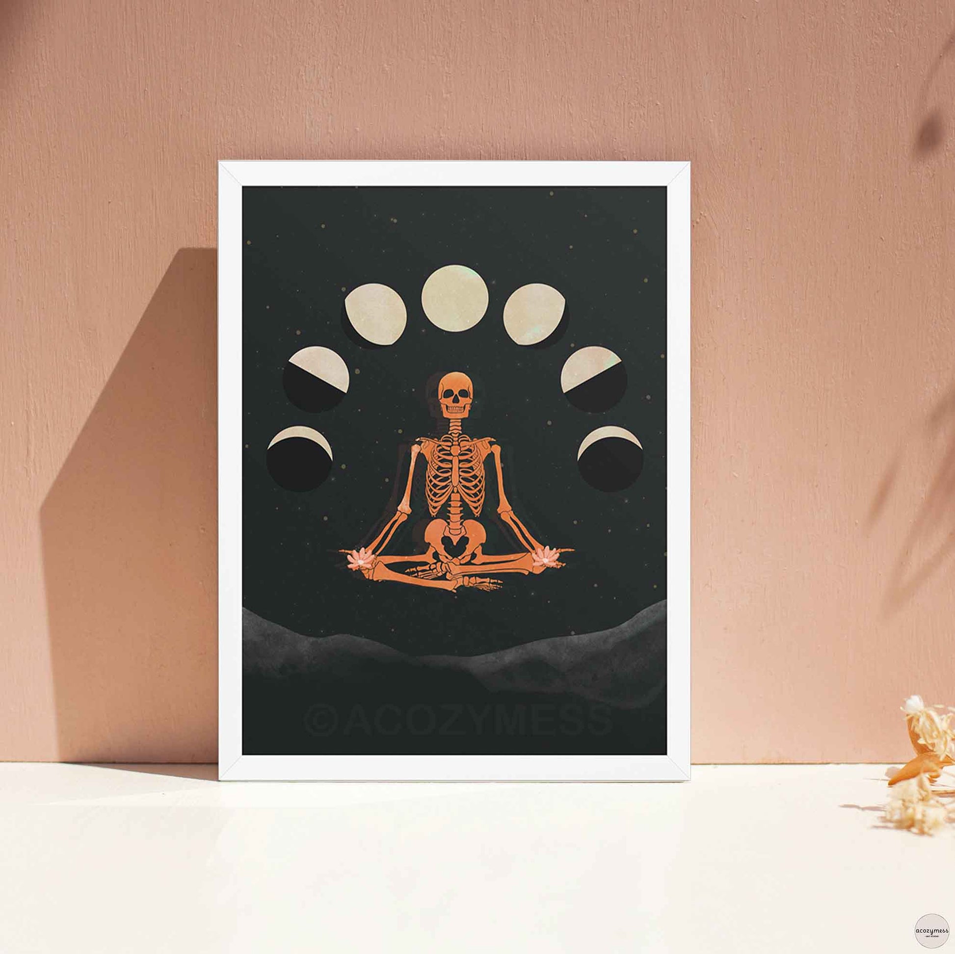  Poster of meditating skeleton with moon phases in white frame, offering a soft balance to the bold mystical artwork.