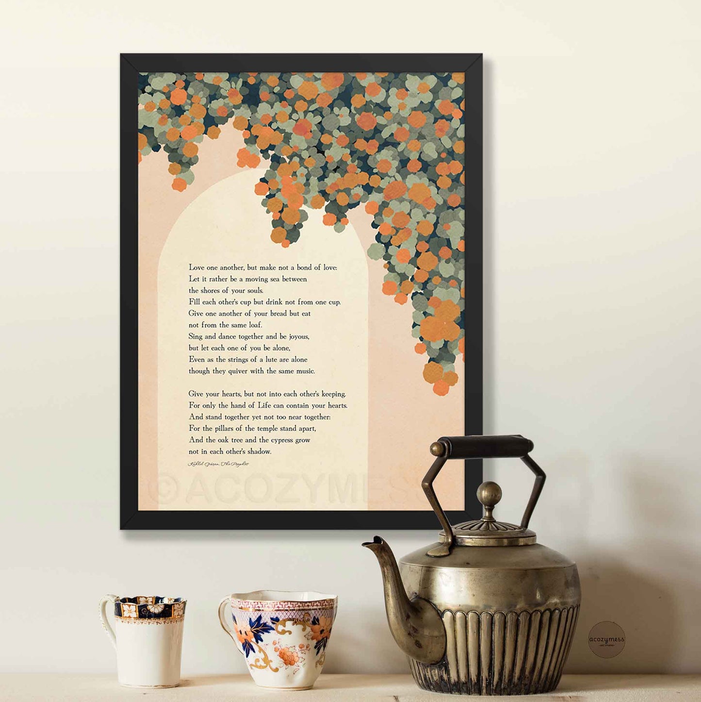 A framed art print featuring a poem with an orange  floral tree illustration, displayed on a wall above a vintage-style metal teapot and two ceramic mugs.