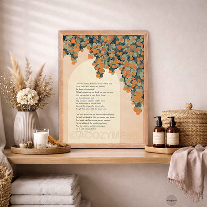 A light wooden framed art print featuring a Kahlil Gibran poem with an orange  leafy tree illustration, styled on a wooden shelf.
