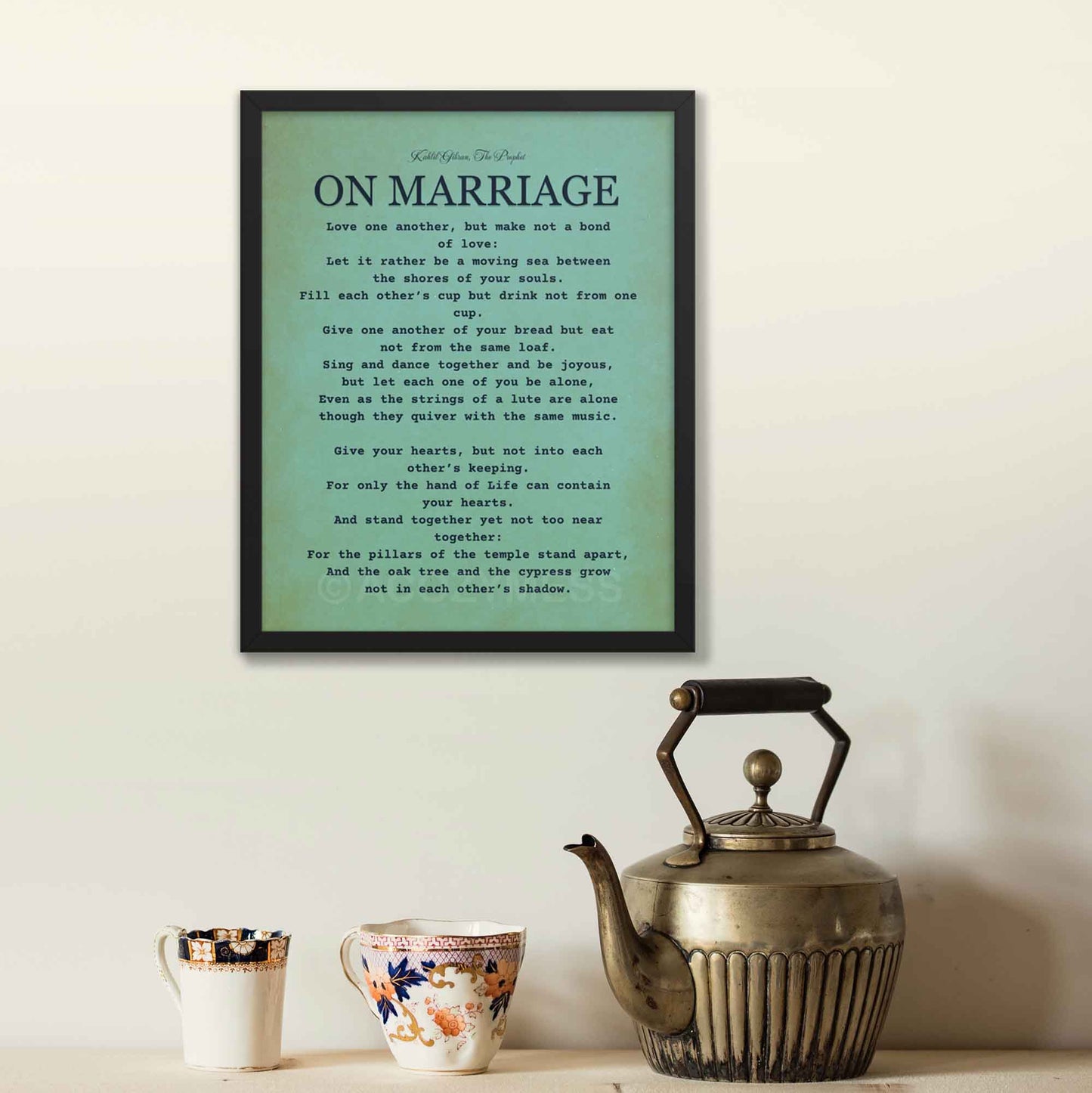 Kahlil Gibran print On Marriage, black on textured  bluish green background, displayed in black frame.