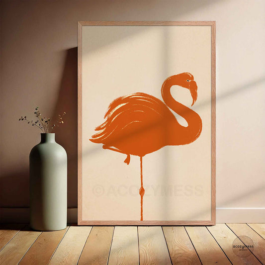 Framed artwork of a stylized orange flamingo on a beige background, leaning against a wall.