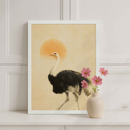A framed art print featuring a black-and-white ostrich walking in front of a warm beige background with a soft orange sun, styled on a white shelf.