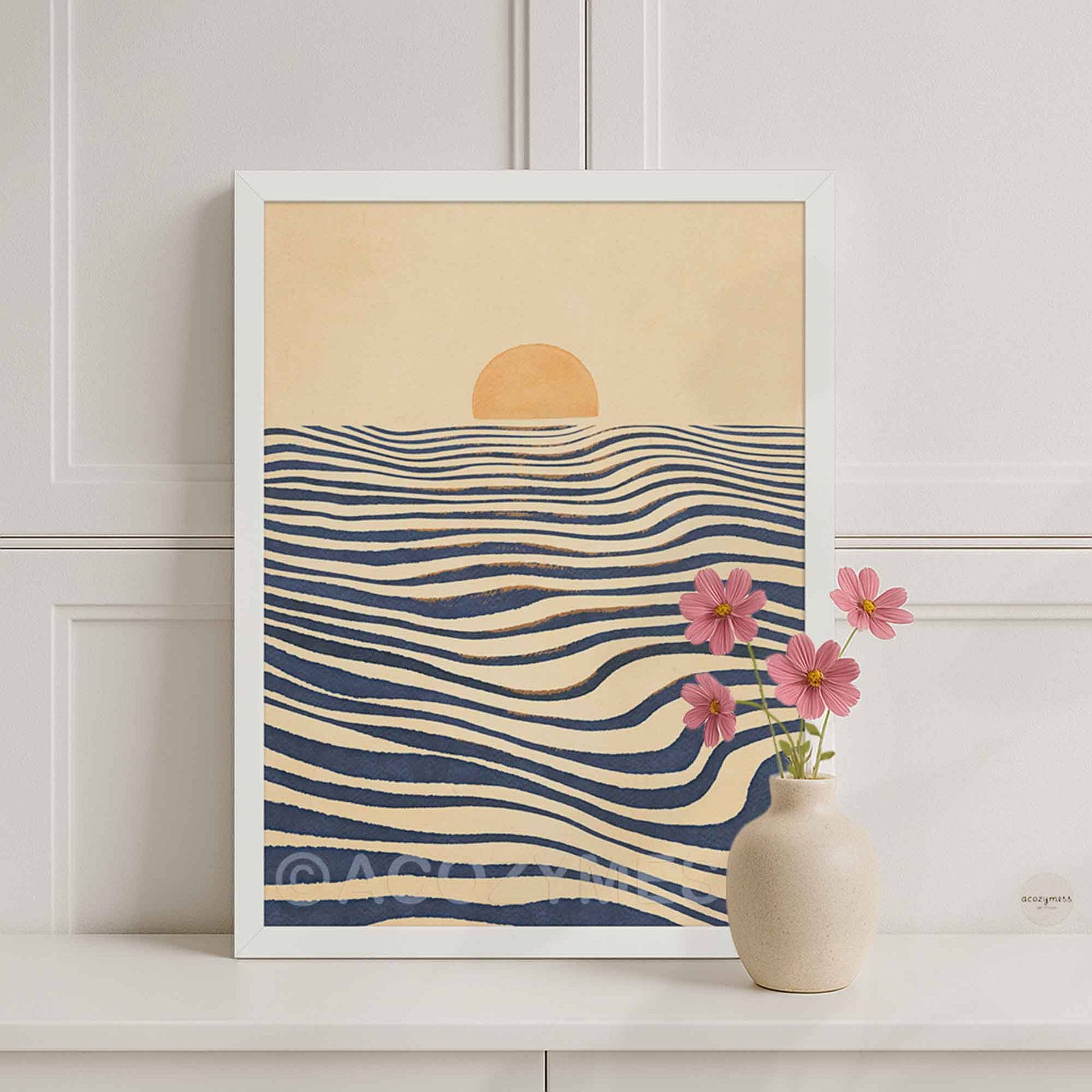 A white framed art print featuring a minimalist sunset over wavy navy blue sea waves.