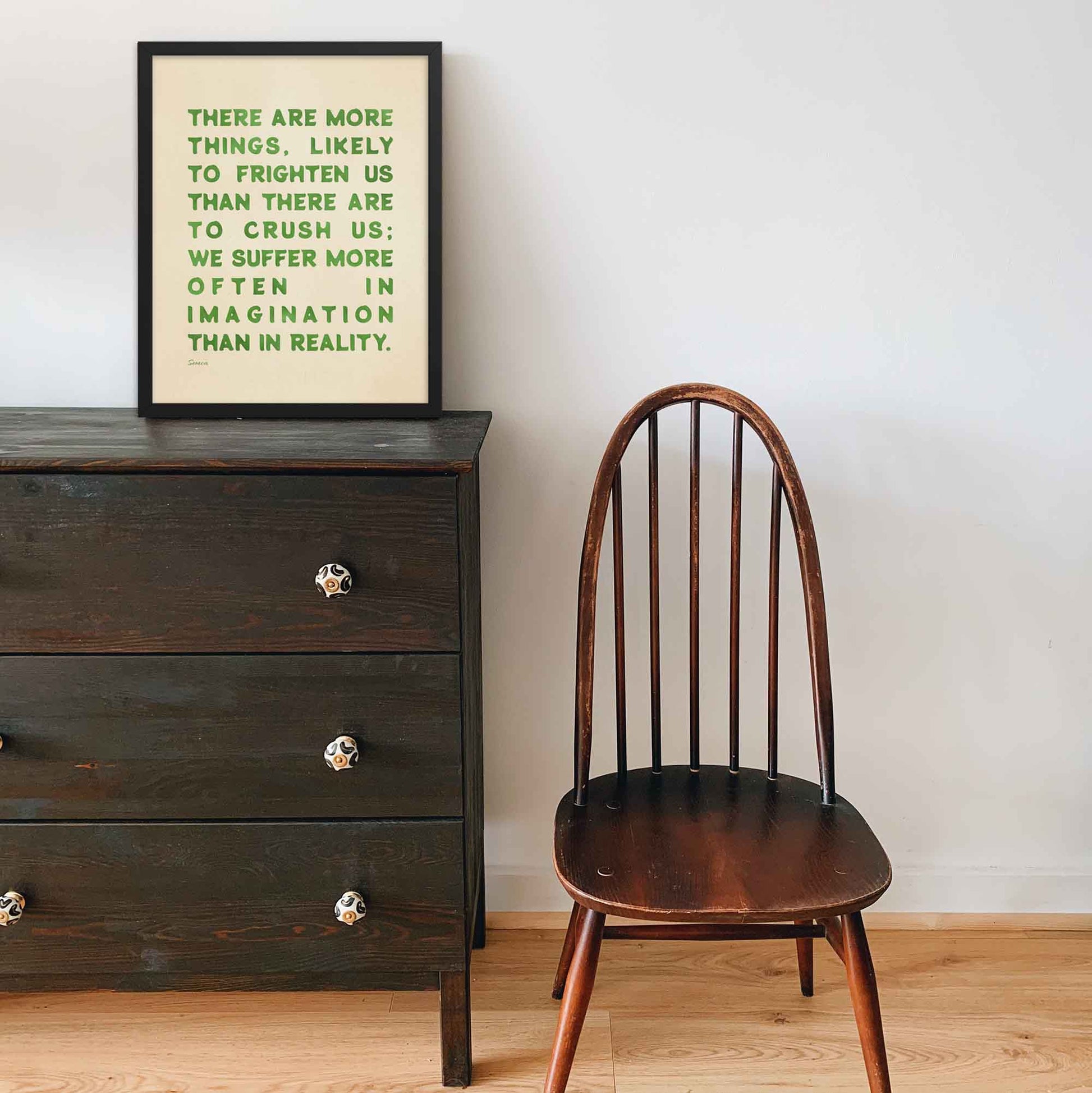 Seneca Poster with quote on fear, green on beige, displayed in black frame