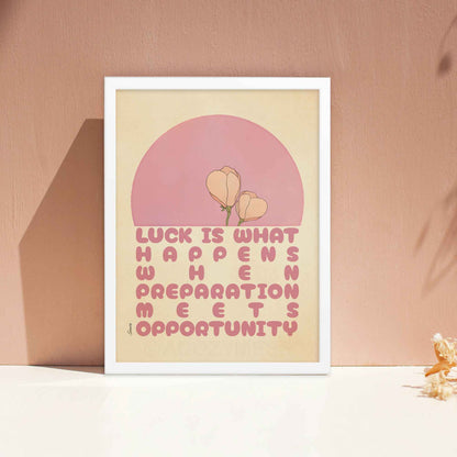 Seneca poster with the quote, Luck is what happens when preparation meets opportunity, in pink and beige with a delicate floral design, displayed in a white frame. 