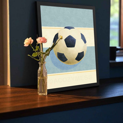 Soccer ball print in a black frame, high-contrast modern wall art on soft light blue and beige tones.