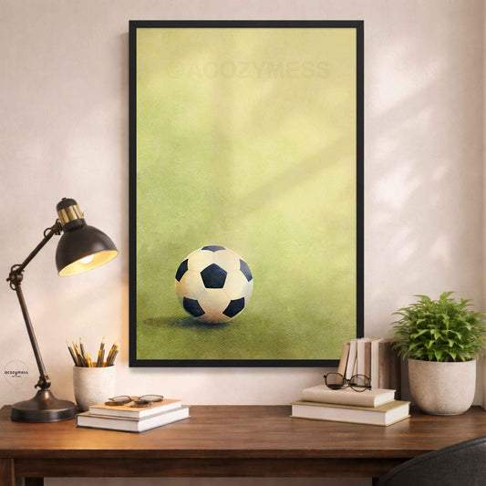 Black Framed poster of a soccer ball on grass on a wall above a desk.