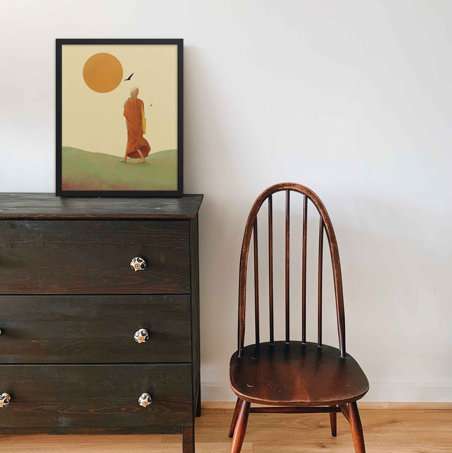 Wall art featuring a monk walking towards the sun, symbolizing the journey towards inner peace and enlightenment in earthly hues of green ywellow and orange on beige background framed in black