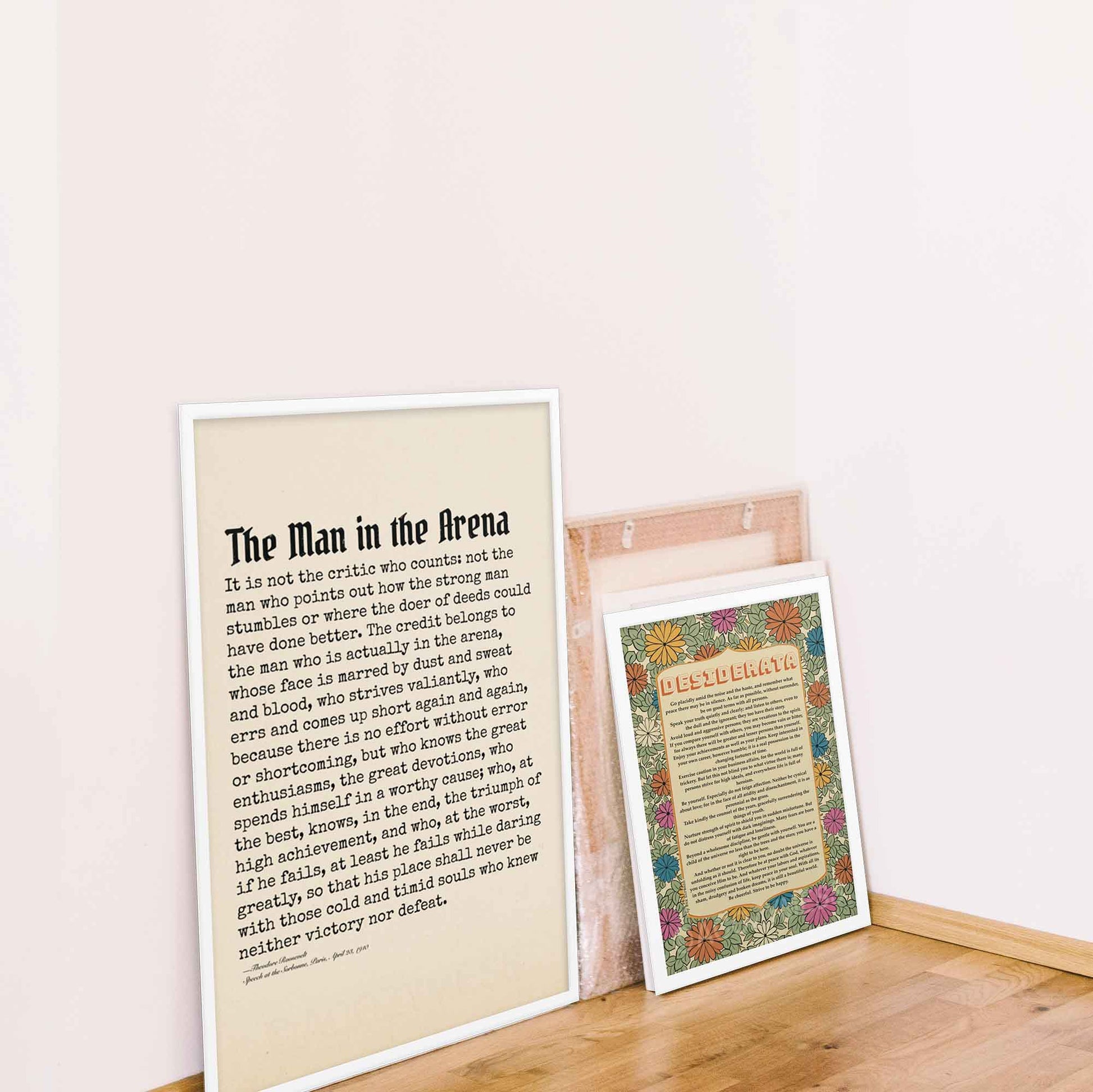 The Man in the Arena poster black on beige, featuring Theodore Roosevelt's iconic quote in white frame along with desiderata poem poster in white frame.