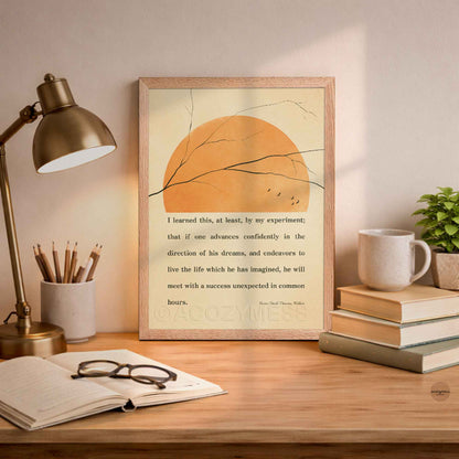 Inspirational Thoreau poster framed in oakwood with minimalist nature elements on beige background on a desk with lamp, books, and mug.