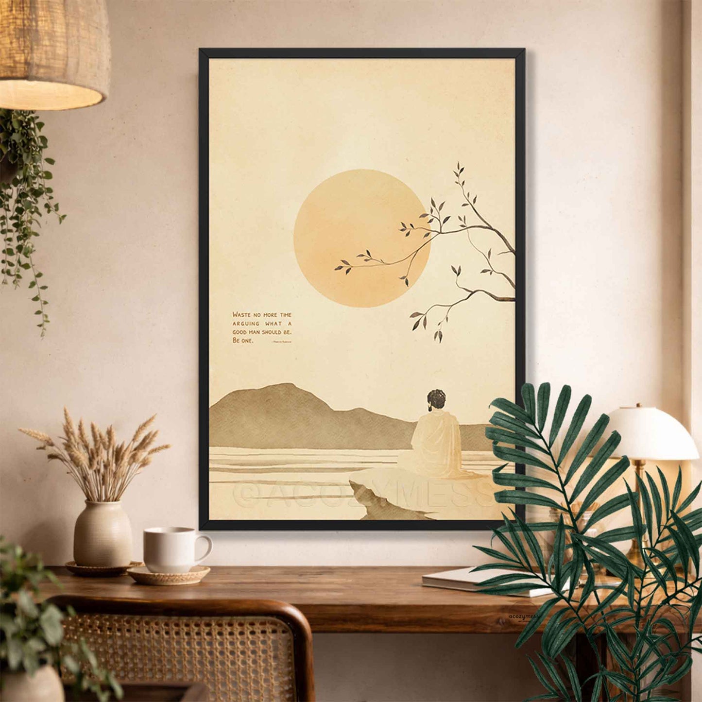 Black Framed Stoic art  of a person by a lake with a large sun, placed on a wall above a wooden desk.