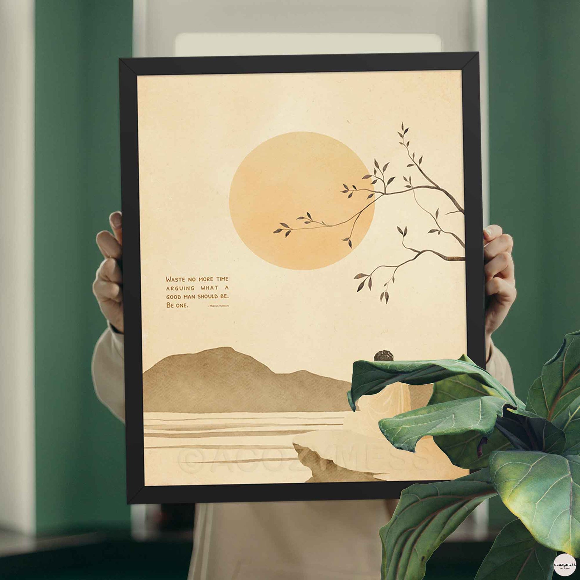 Black Stoic Quote Framed artwork with a minimalist design of a sun, branch, and mountains held by a person.