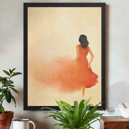 Framed artwork of a woman in an orange dress on a beige background, placed on a wall with plants and a coffee cup below.