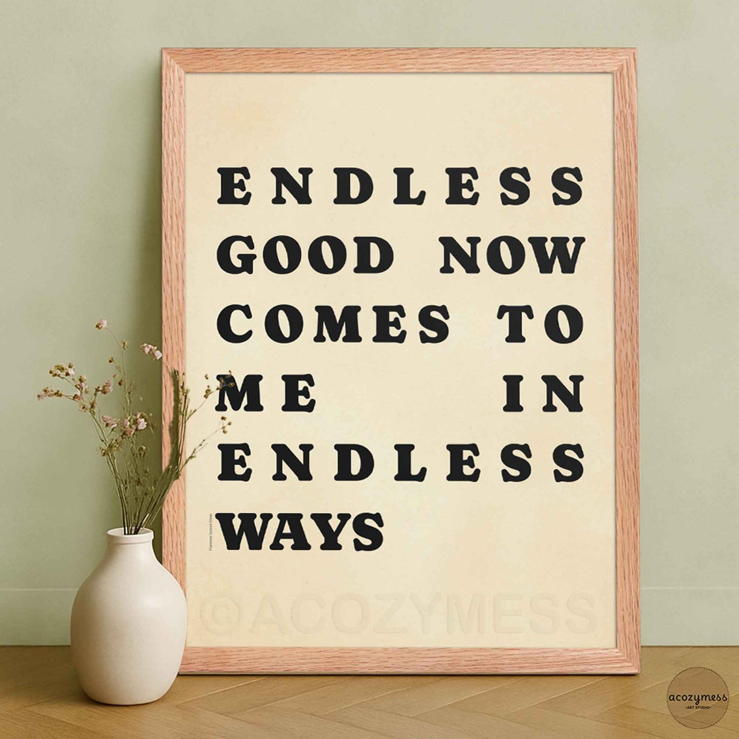 Framed poster with motivational quote 'Endless good now comes to me in endless ways' on a beige background, next to a white vase with dried flowers.