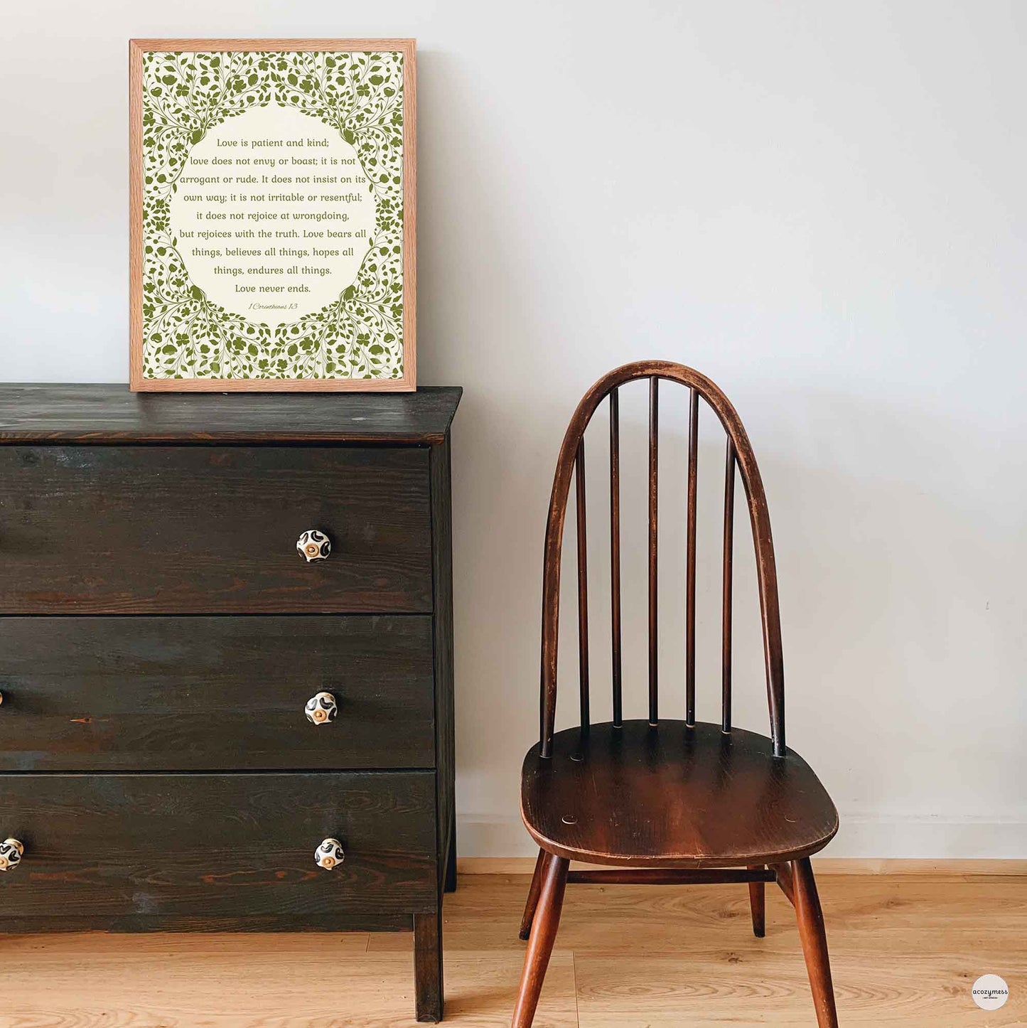 “Love is patient, love is kind” poster in a natural oakwood frame, featuring green floral artwork on a beige background—perfect for warm, rustic interiors.