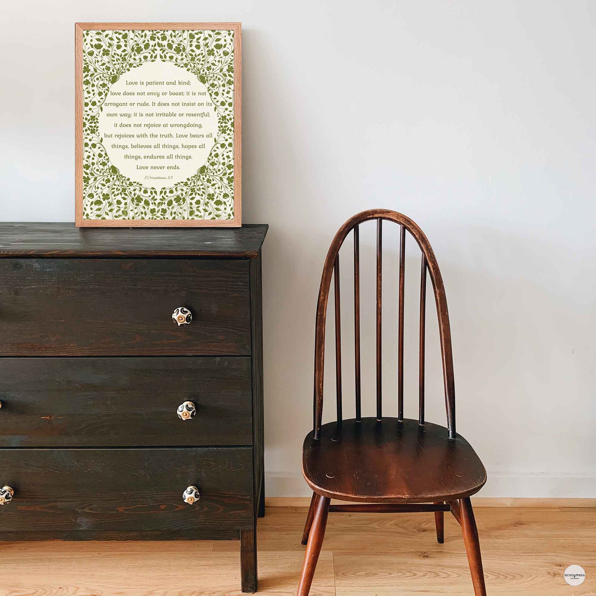 “Love is patient, love is kind” poster in a natural oakwood frame, featuring green floral artwork on a beige background—perfect for warm, rustic interiors.