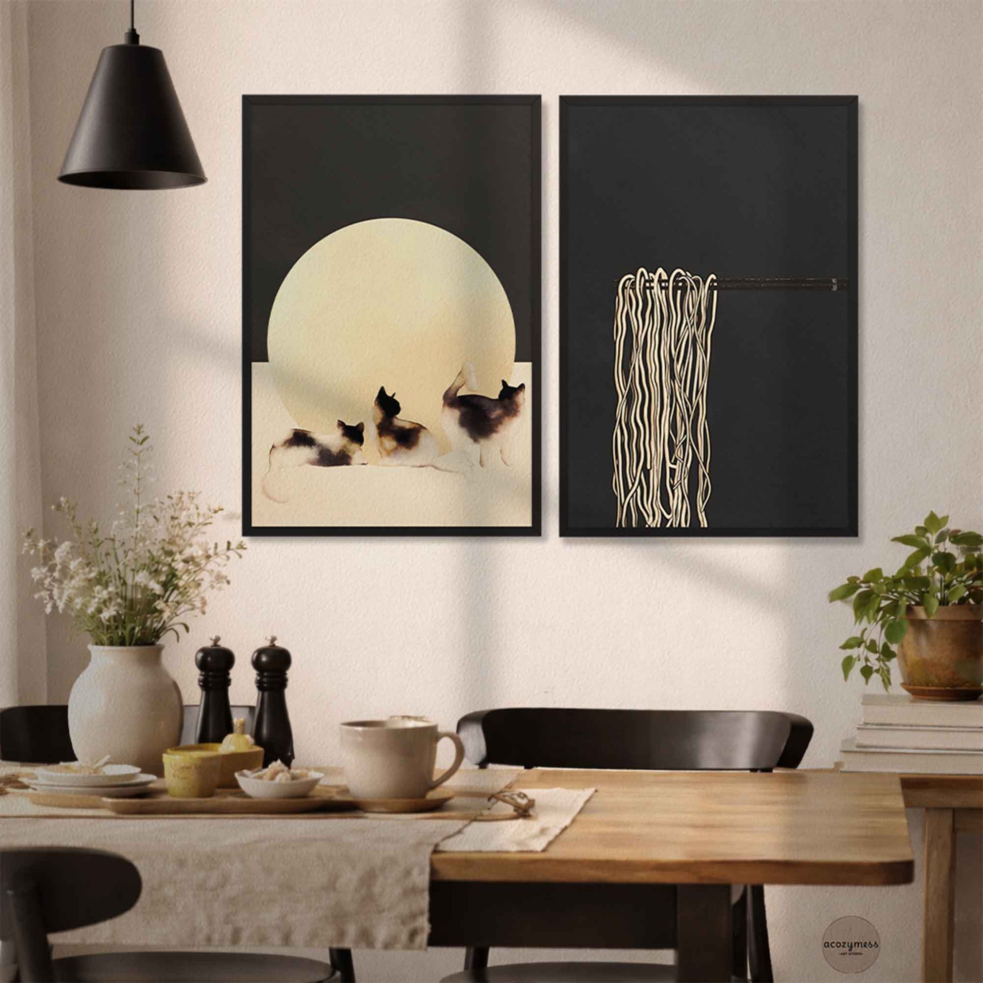 Dining room with two framed artworks of three cats and noodles on a chopsticks in black frames on the wall above a table.