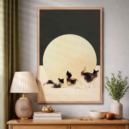 Framed artwork of three cats under a moonlit sky in a home setting.