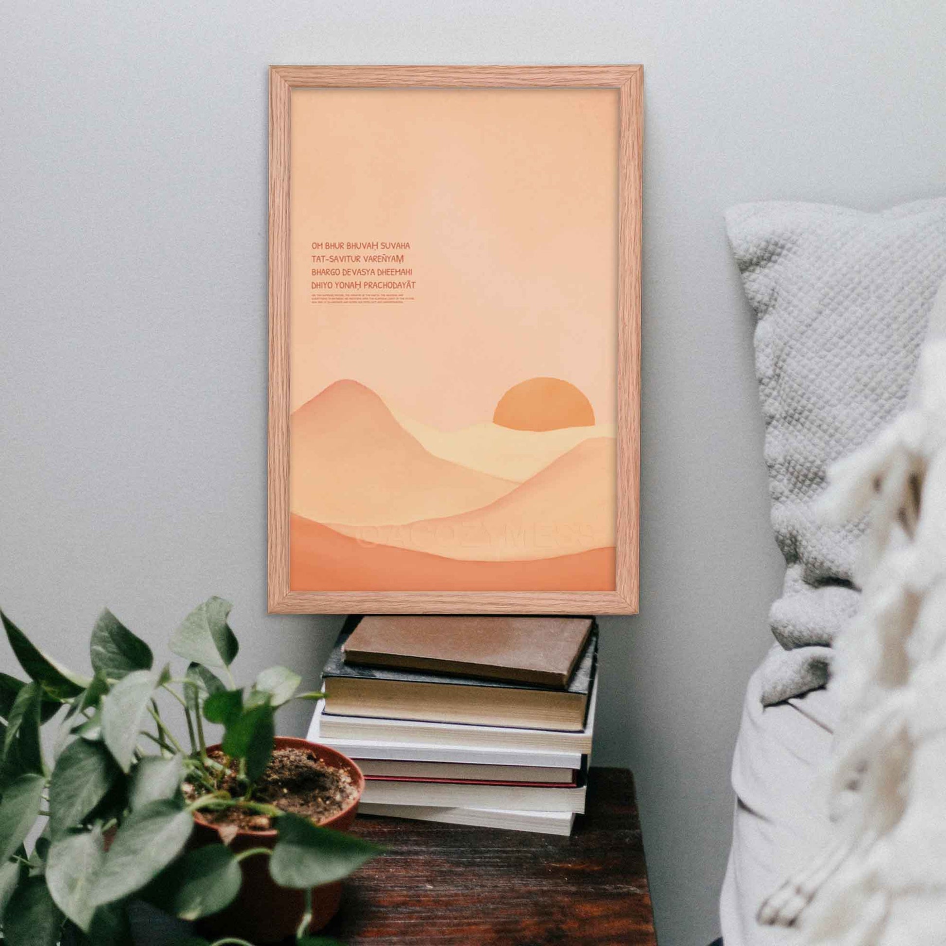 Gayatri Mantra poster featuring calming landscape art in a light color palette, displayed in a oakwood frame, on side table.