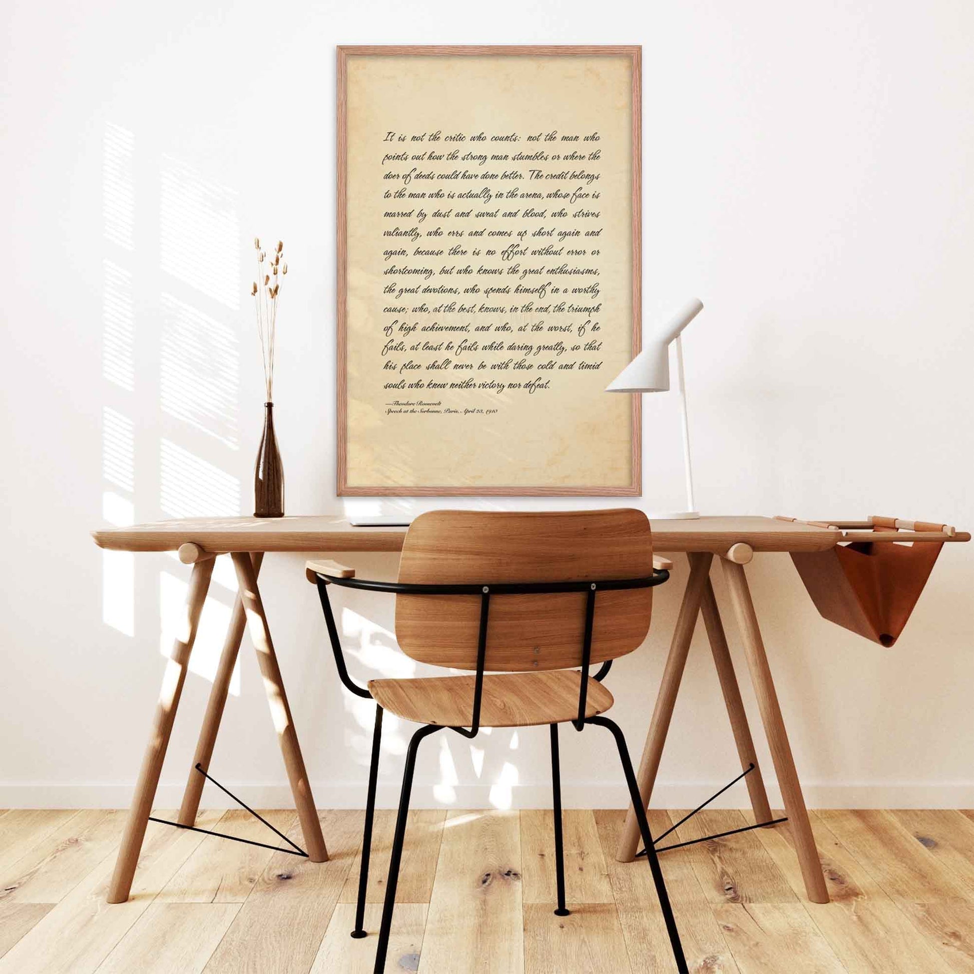 The Man in the Arena poster featuring Theodore Roosevelt's iconic quote, available in oakwood frame on a desk wall.