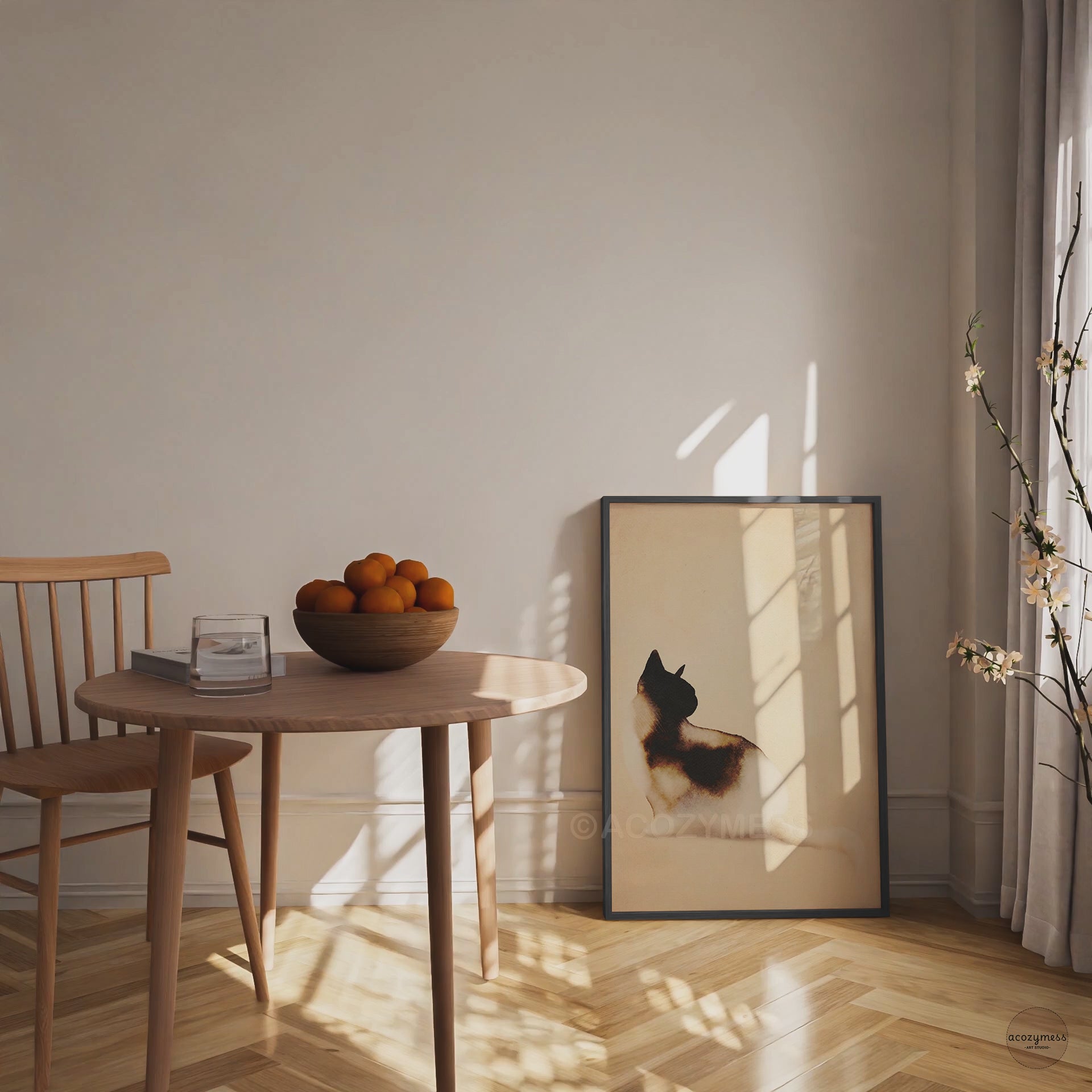 Video of a black framed minimalist watercolor cat art poster leaning on the floor beside a wooden dining table in warm sunlight