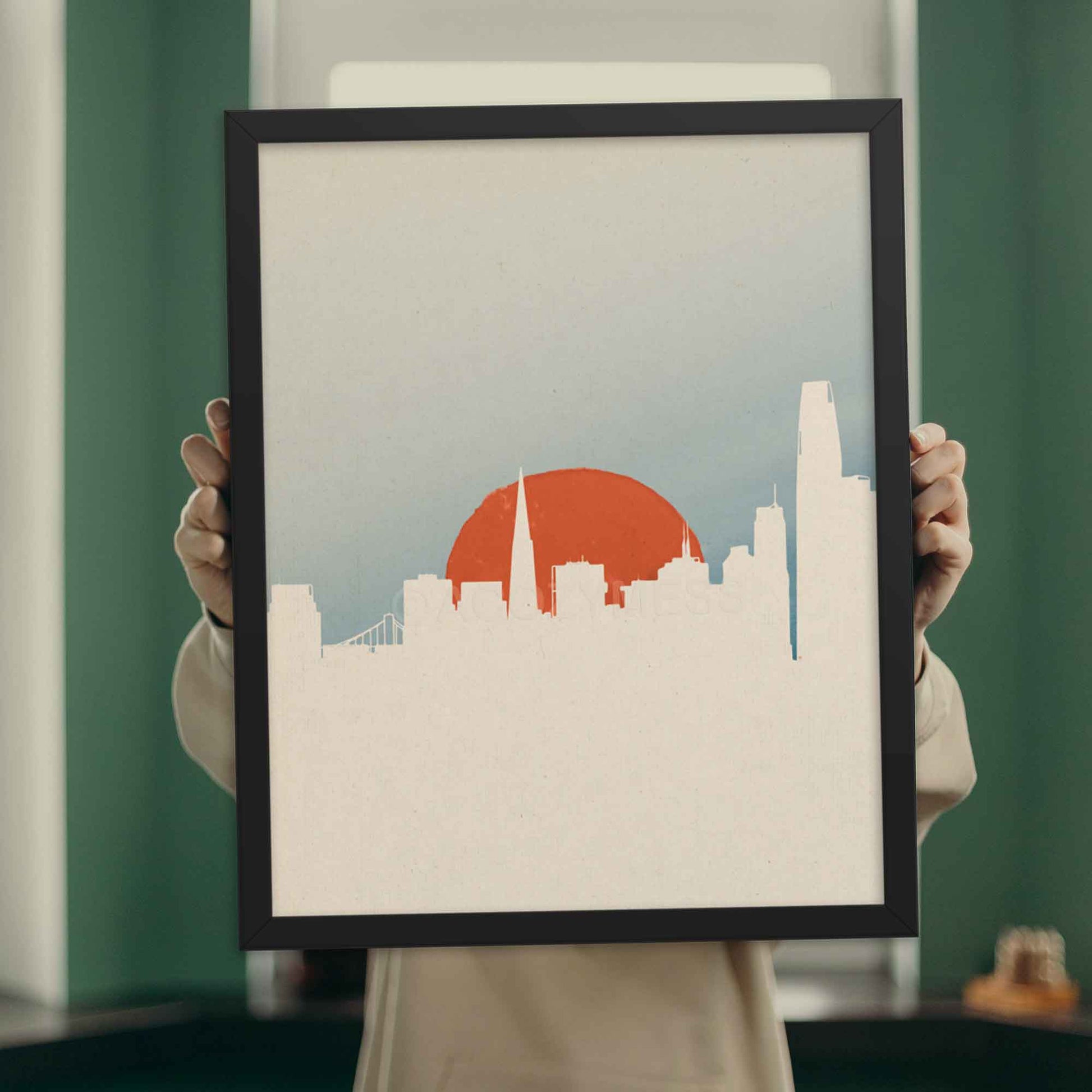 San Francisco skyline poster with minimal color palette and design in white, orange and blue, displayed in black frame.