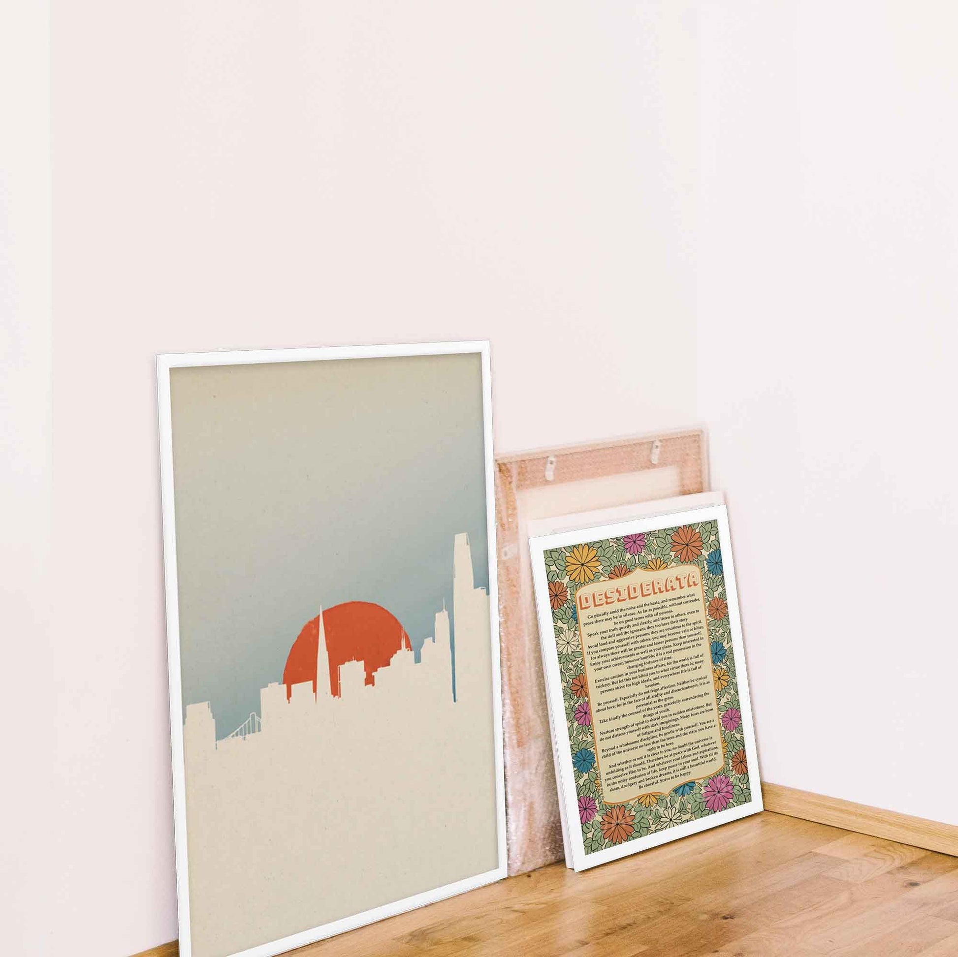 San Francisco skyline art poster with minimal color palette and design in white, orange and blue, displayed in white frame.