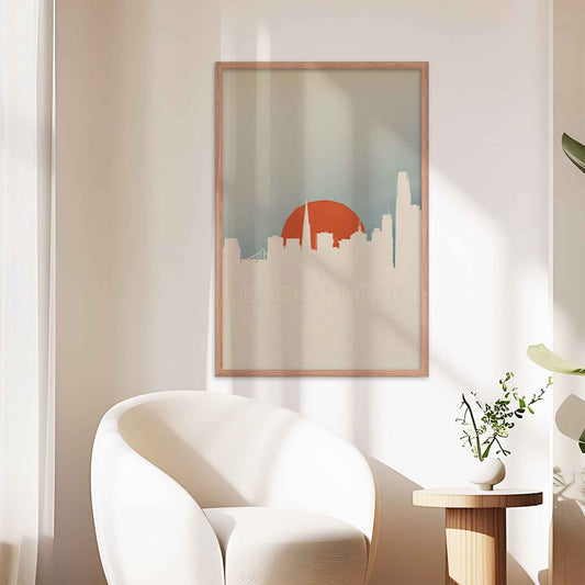 San Francisco skyline poster with minimal color palette and design in white, orange and blue, displayed in oak frame on a office wall.