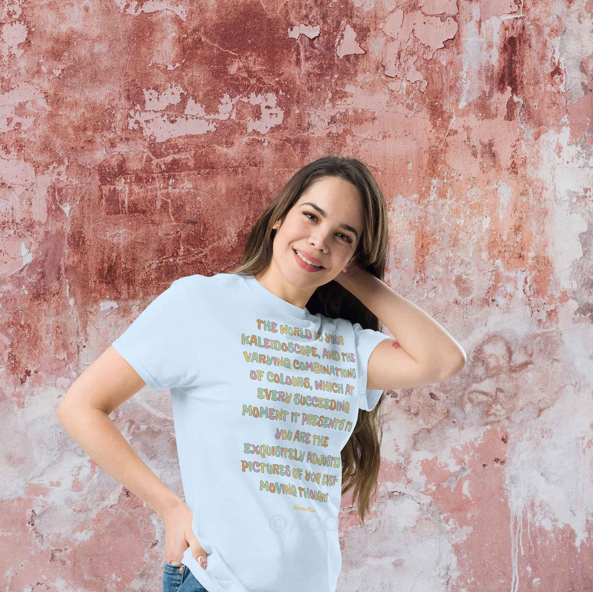 A woman wearing light blue Tee featuring an inspiring quote by James Allen: The world is your kaleidoscope, and the varying combinations of colors, which at every succeeding moment it presents to you are the exquisitely adjusted pictures of your ever-moving thoughts.