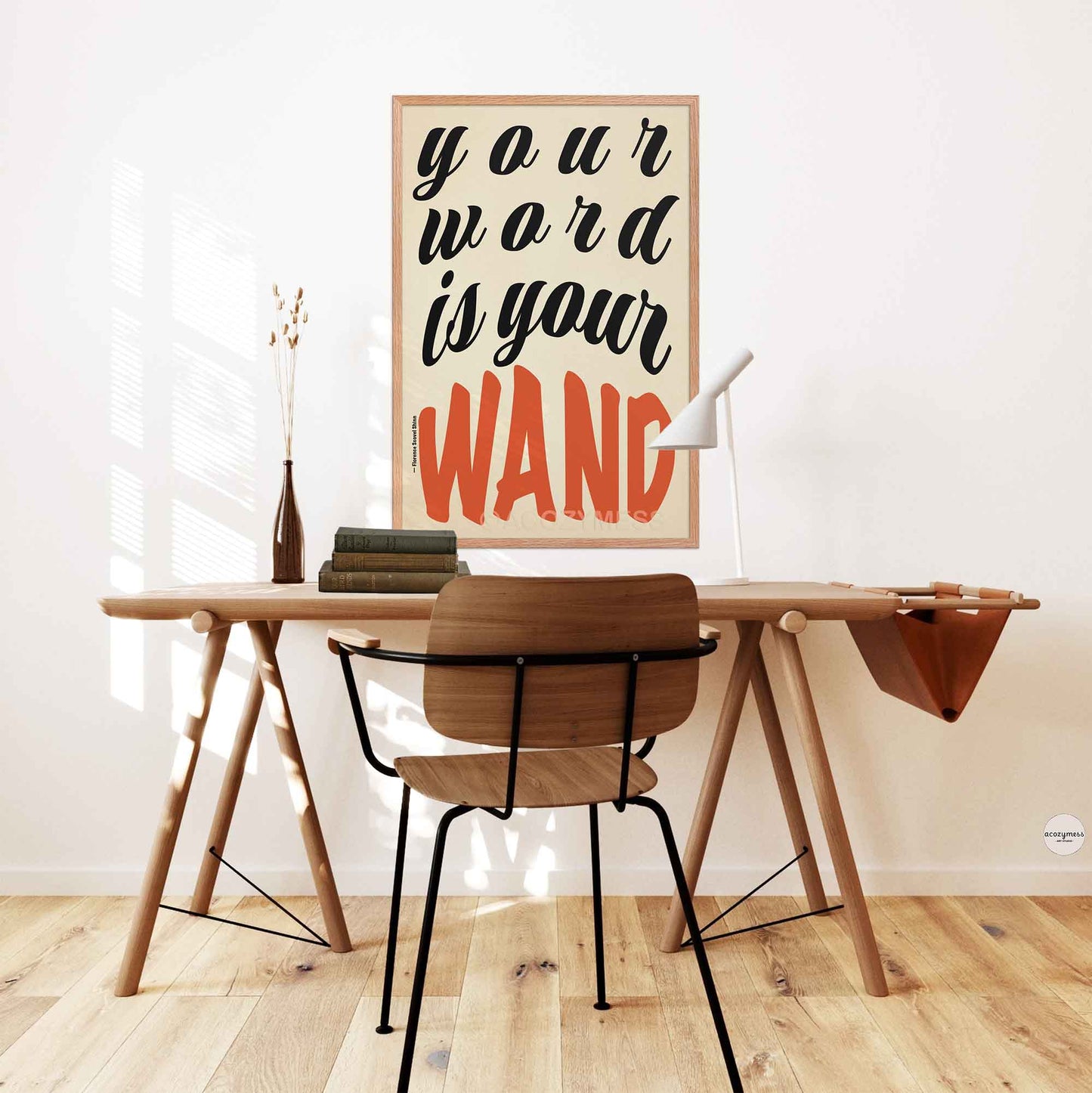 Framed poster of Florence Shinn’s quote “Your Word Is Your Wand” in black and red typography on beige, displayed in an oakwood frame .motivational poster on a white wall