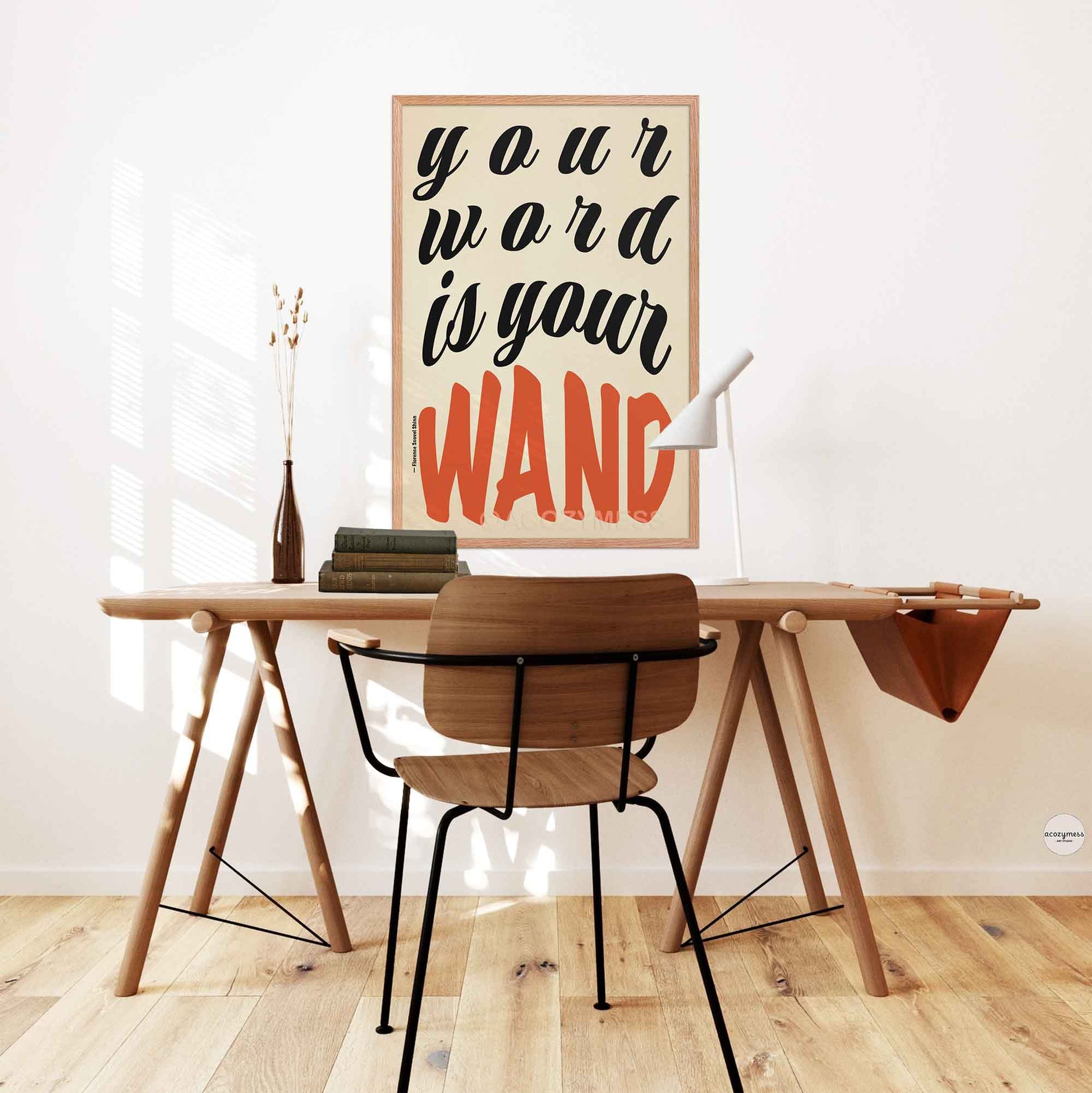 Framed poster of Florence Shinn’s quote “Your Word Is Your Wand” in black and red typography on beige, displayed in an oakwood frame .motivational poster on a white wall