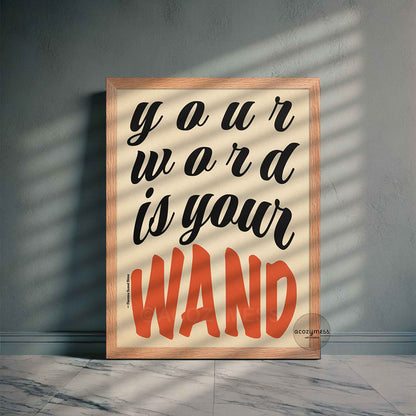 Framed poster of Florence Shinn’s quote “Your Word Is Your Wand” in black and red typography on beige, displayed in an oakwood frame on a neutral-toned wall.